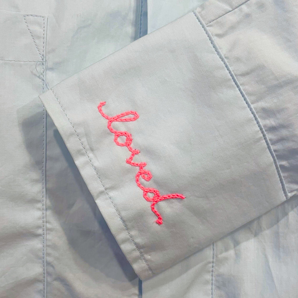 Image of a button down cuff with a custom embroidery that says "loved"